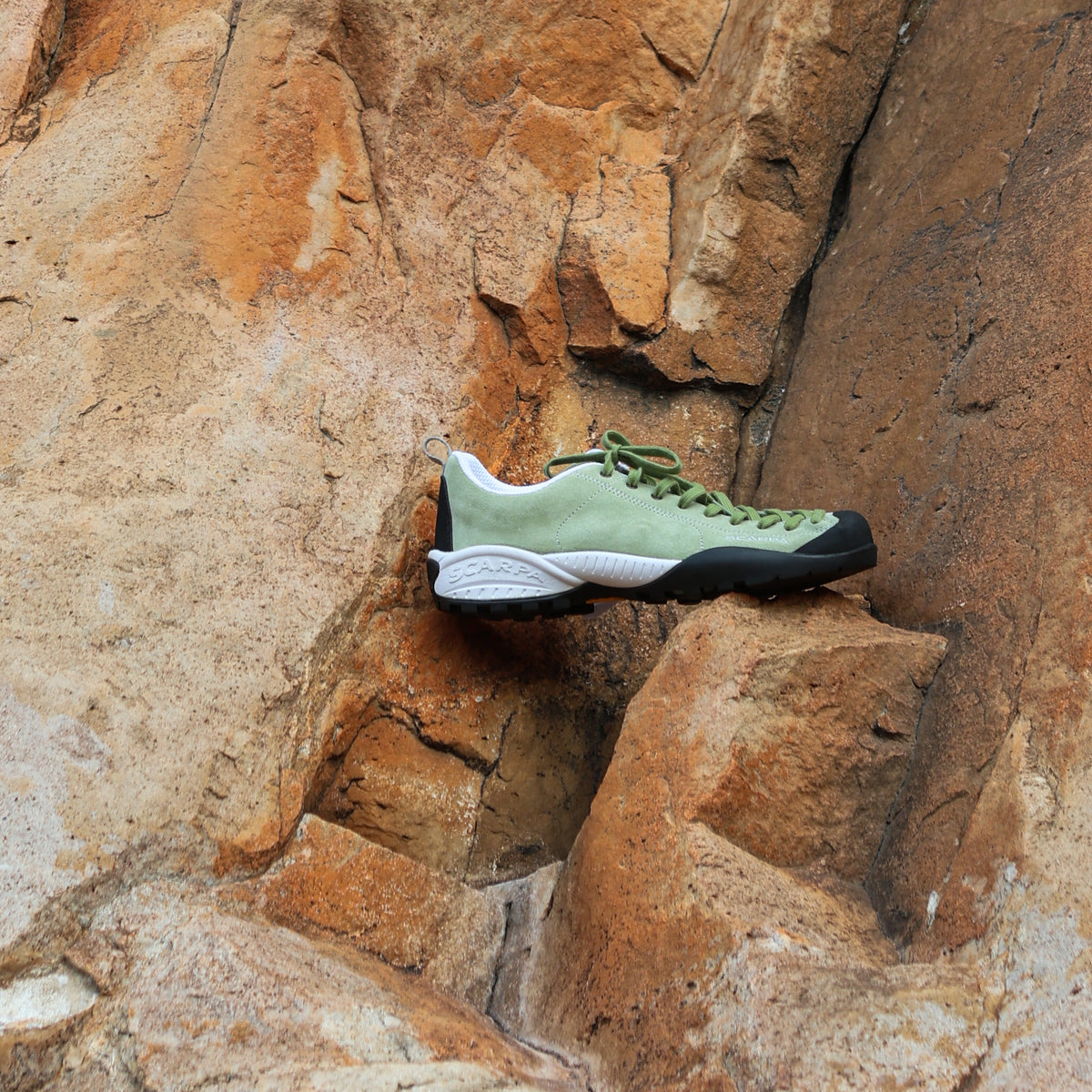 Green climbing shoe on a rocky surface